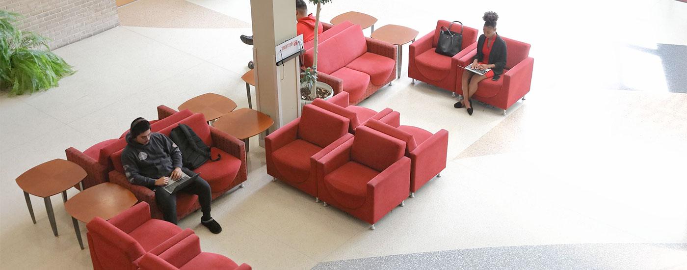 Two students sit in the Lane Center and work on coursework in between their classes